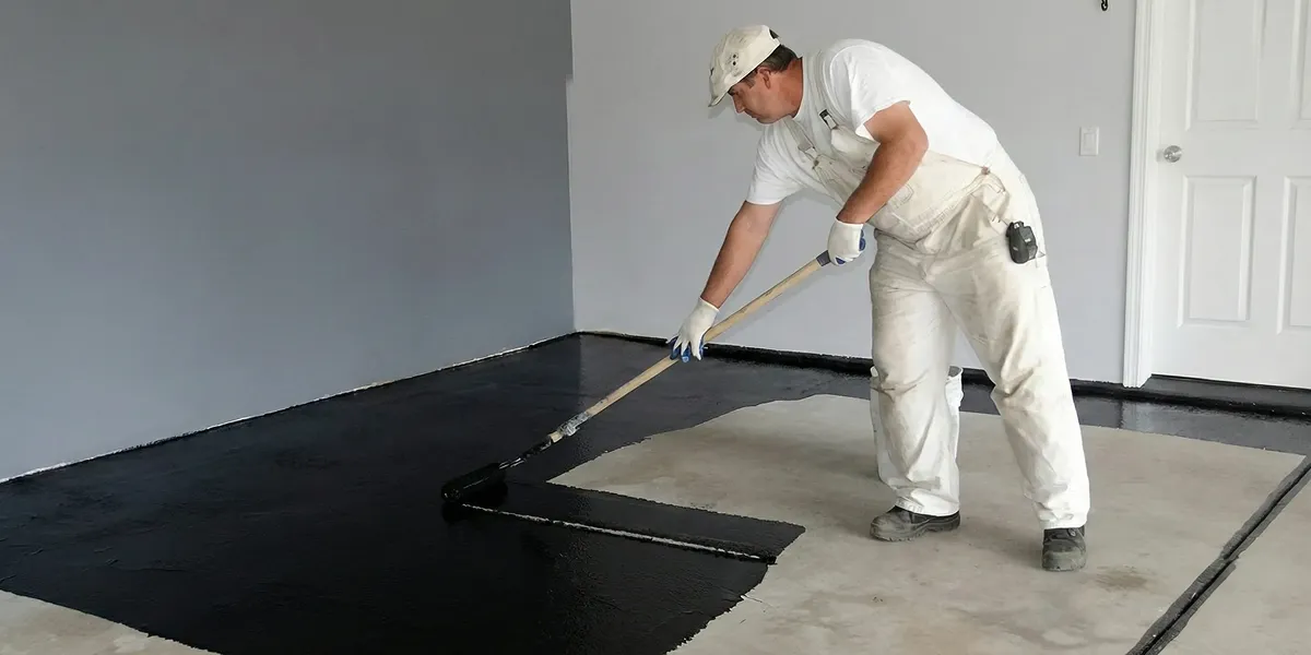 basement waterproofing professional applying waterproof coating to protect a basement floor in Arlington, TX